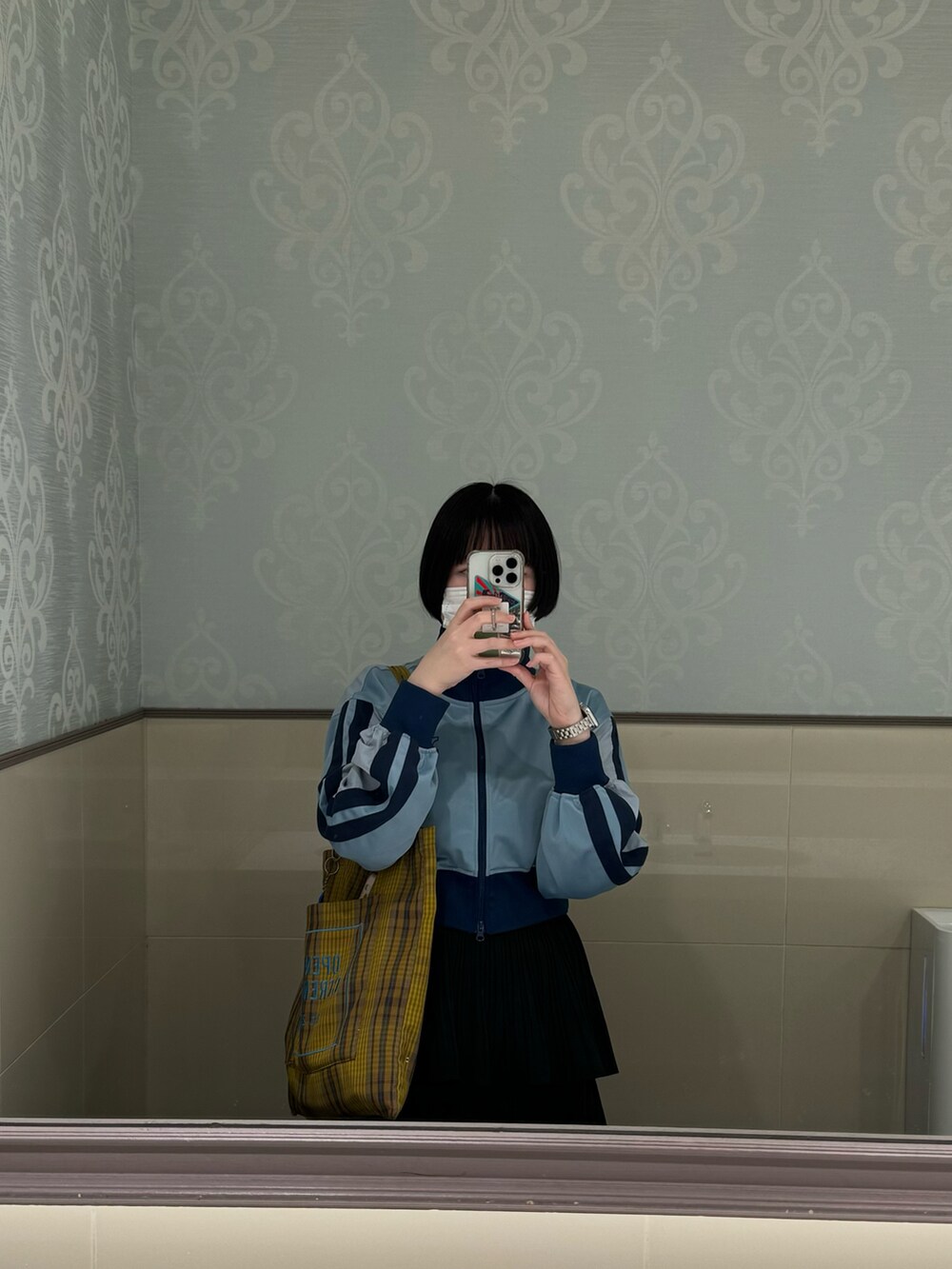 ブルー系のスニーカー、ホワイト系のスカート、ブルー系のナイロンジャケットを着用したレディースの春コーディネートの3枚目の写真