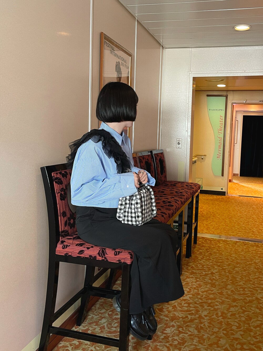 ブラック系のローファー、ブラック系のスカート、ブラック系のハンドバッグを着用したレディースの秋コーディネートの4枚目の写真