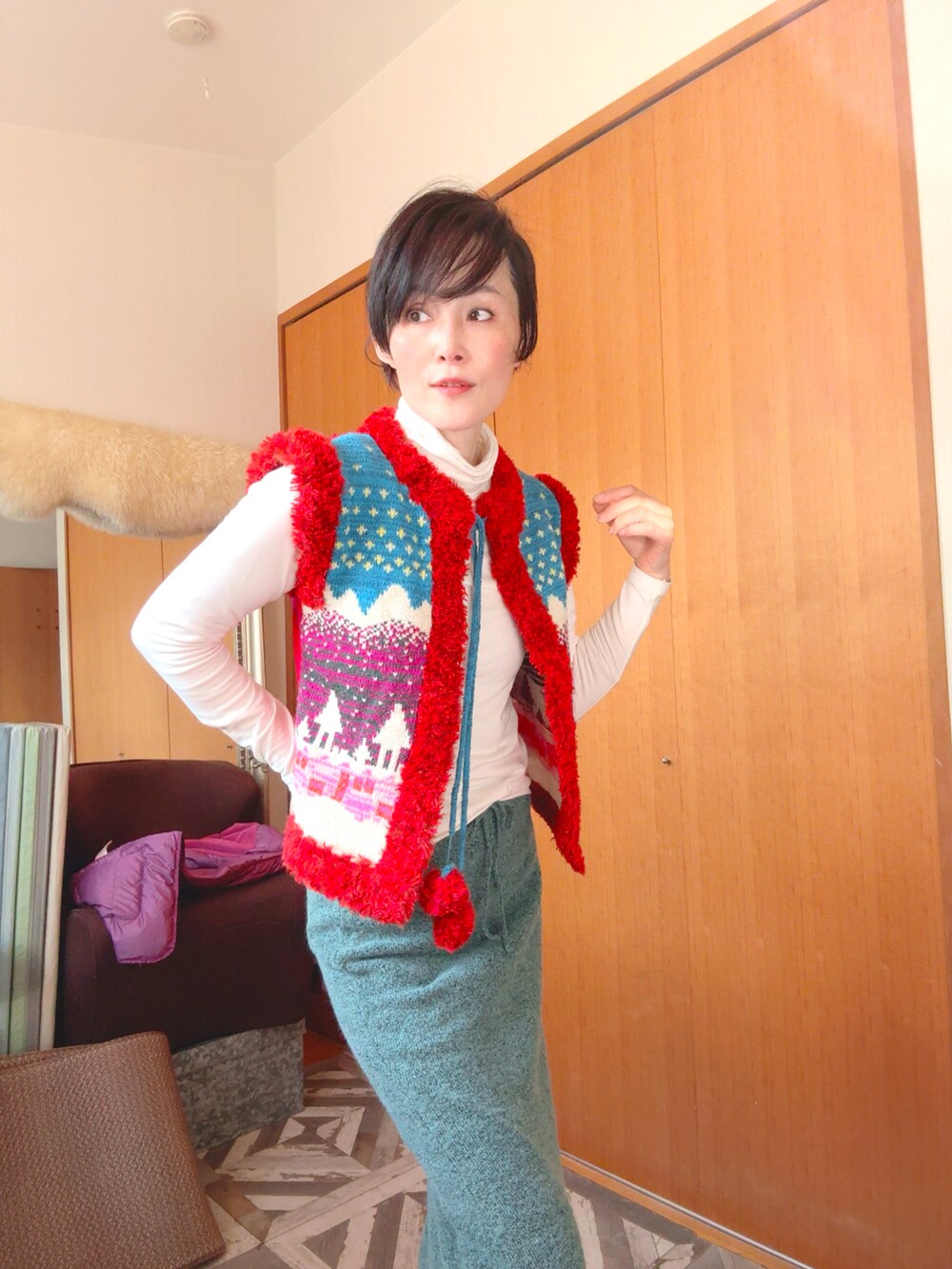 グリーン系のスカート、レッド系のベストを着用したレディースの冬コーディネートの3枚目の写真