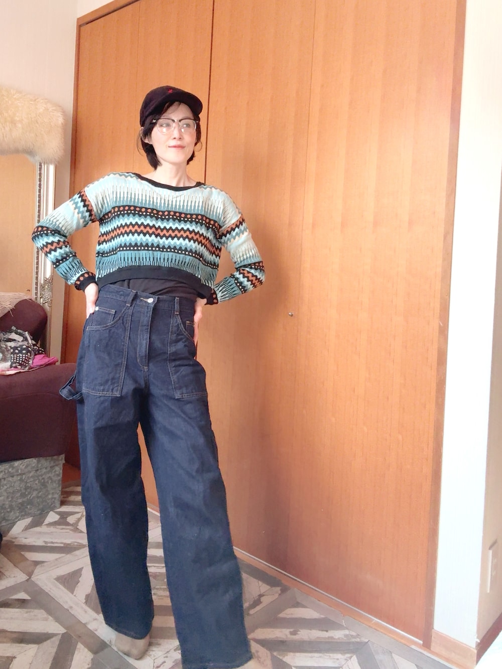 グリーン系のニット/セーター、ブルー系のデニムパンツ、ブラック系のキャップを着用したレディースの冬コーディネートの2枚目の写真