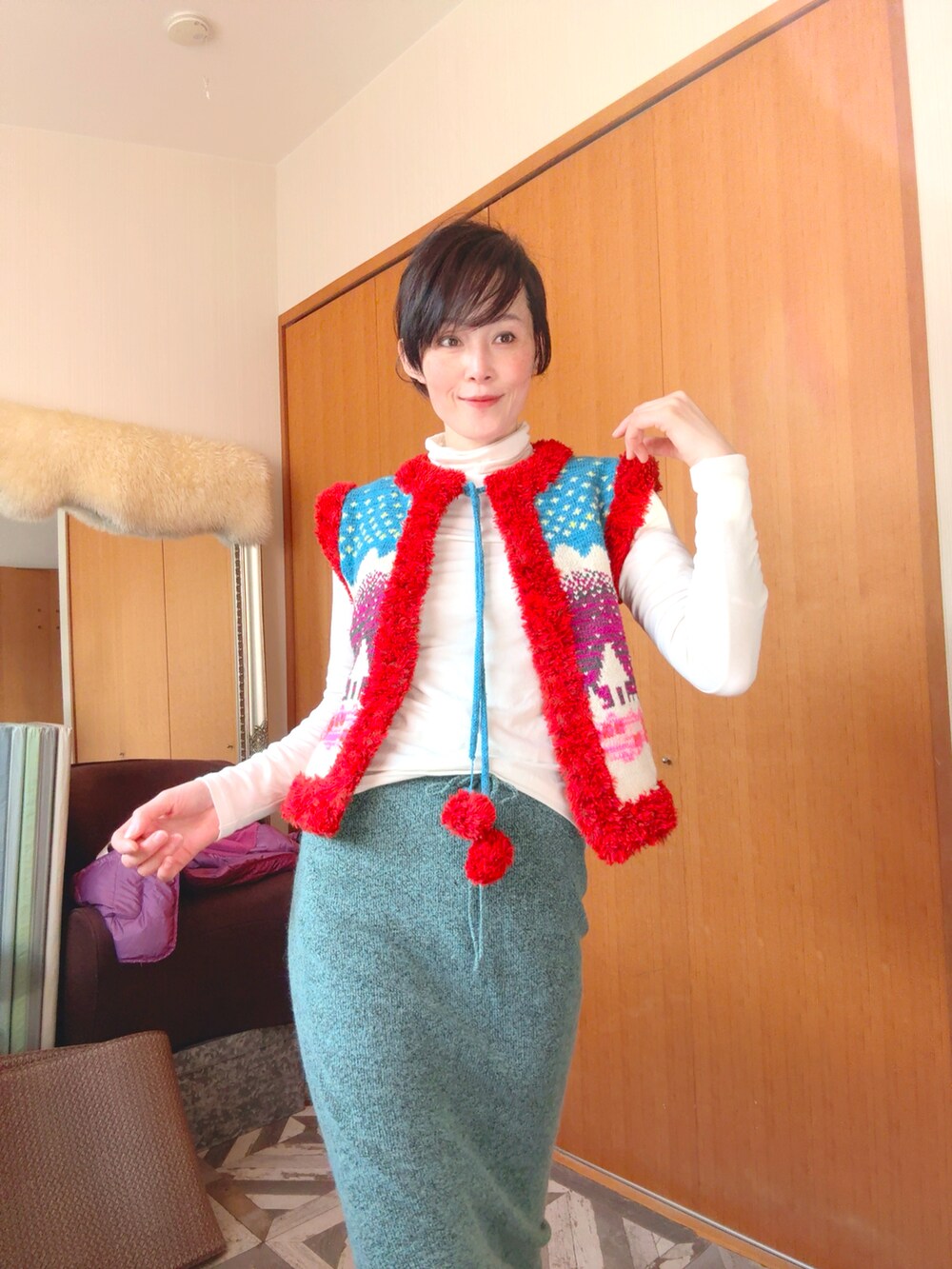 グリーン系のスカート、レッド系のベストを着用したレディースの冬コーディネートの2枚目の写真