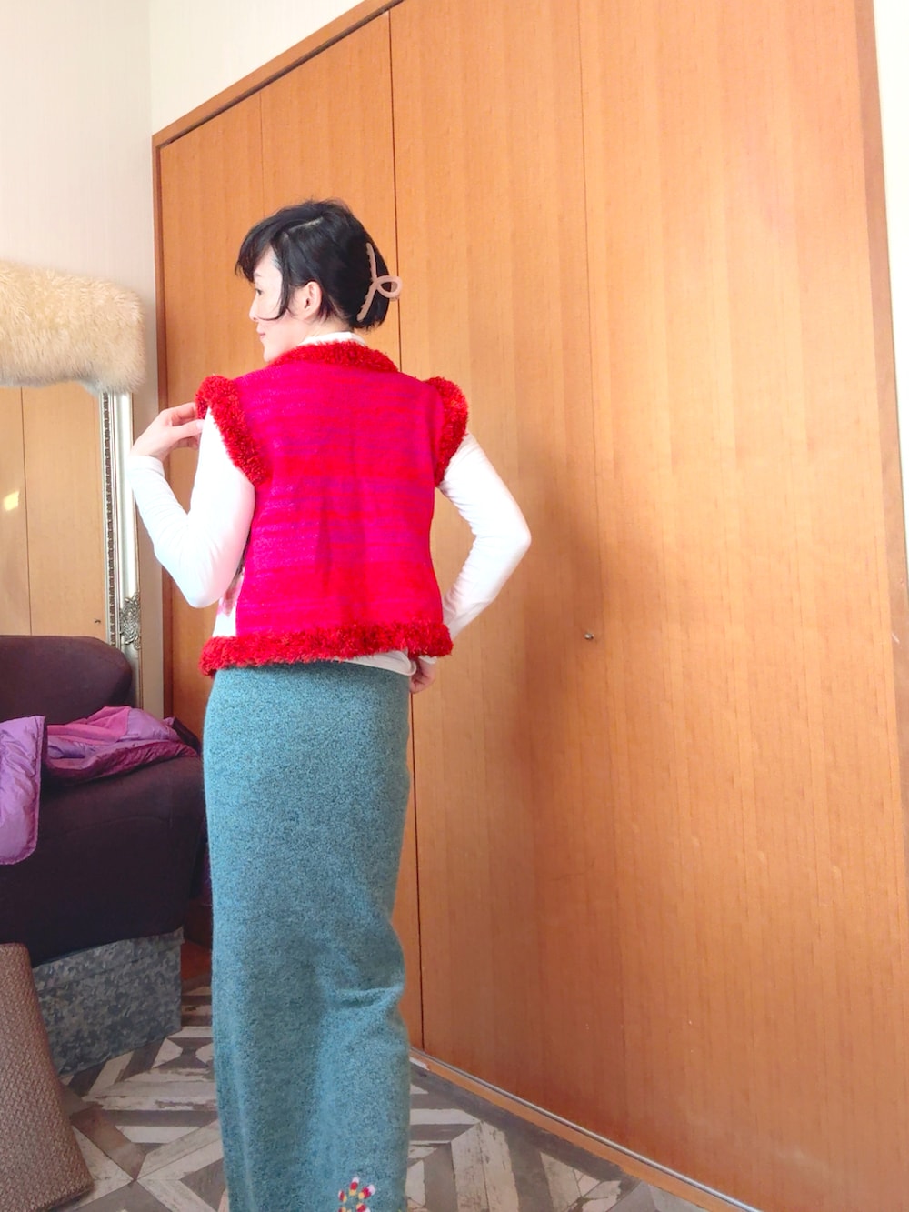 グリーン系のスカート、レッド系のベストを着用したレディースの冬コーディネートの4枚目の写真