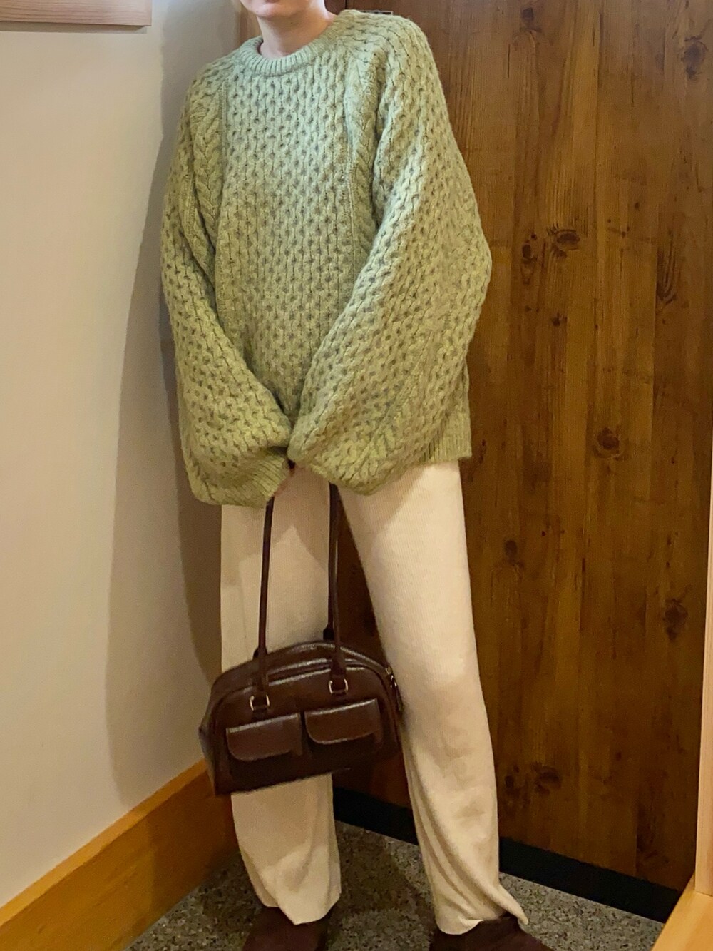 グリーン系のニット/セーター、ブラウン系のショルダーバッグ、ブラウン系のブーツを着用したレディースの冬コーディネートの2枚目の写真