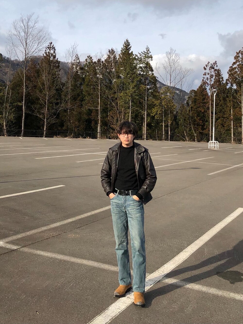 グレー系のデニムパンツ、イエロー系のブーツ、ブラウン系のライダースジャケットを着用したメンズの夏コーディネートの2枚目の写真