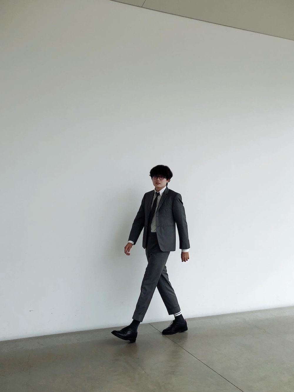 グレー系のスーツセット、ブラック系のローファー、グレー系のネクタイを着用したメンズの夏コーディネートの2枚目の写真