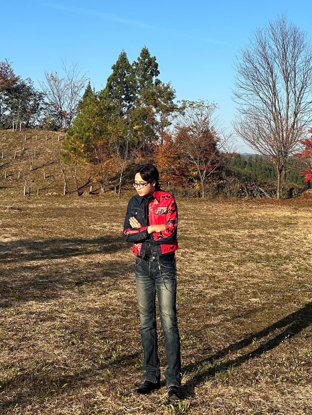 ブルー系のデニムパンツ、レッド系のデニムジャケット、ブラック系のブーツを着用したメンズの夏コーディネートの2枚目の写真