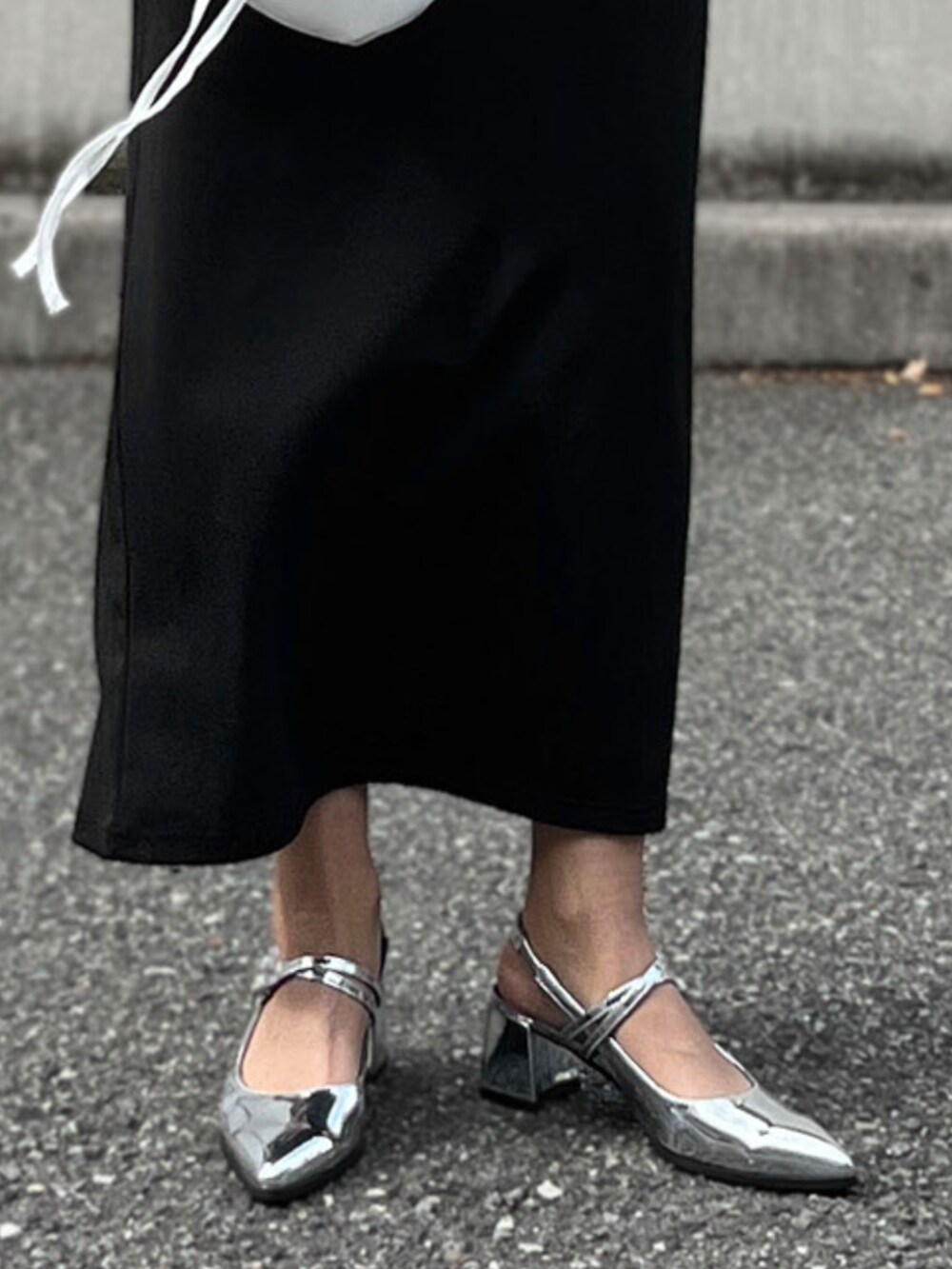 ホワイト系のショルダーバッグ、シルバー系のパンプス、シルバー系のネックレスを着用したレディースの秋コーディネートの2枚目の写真