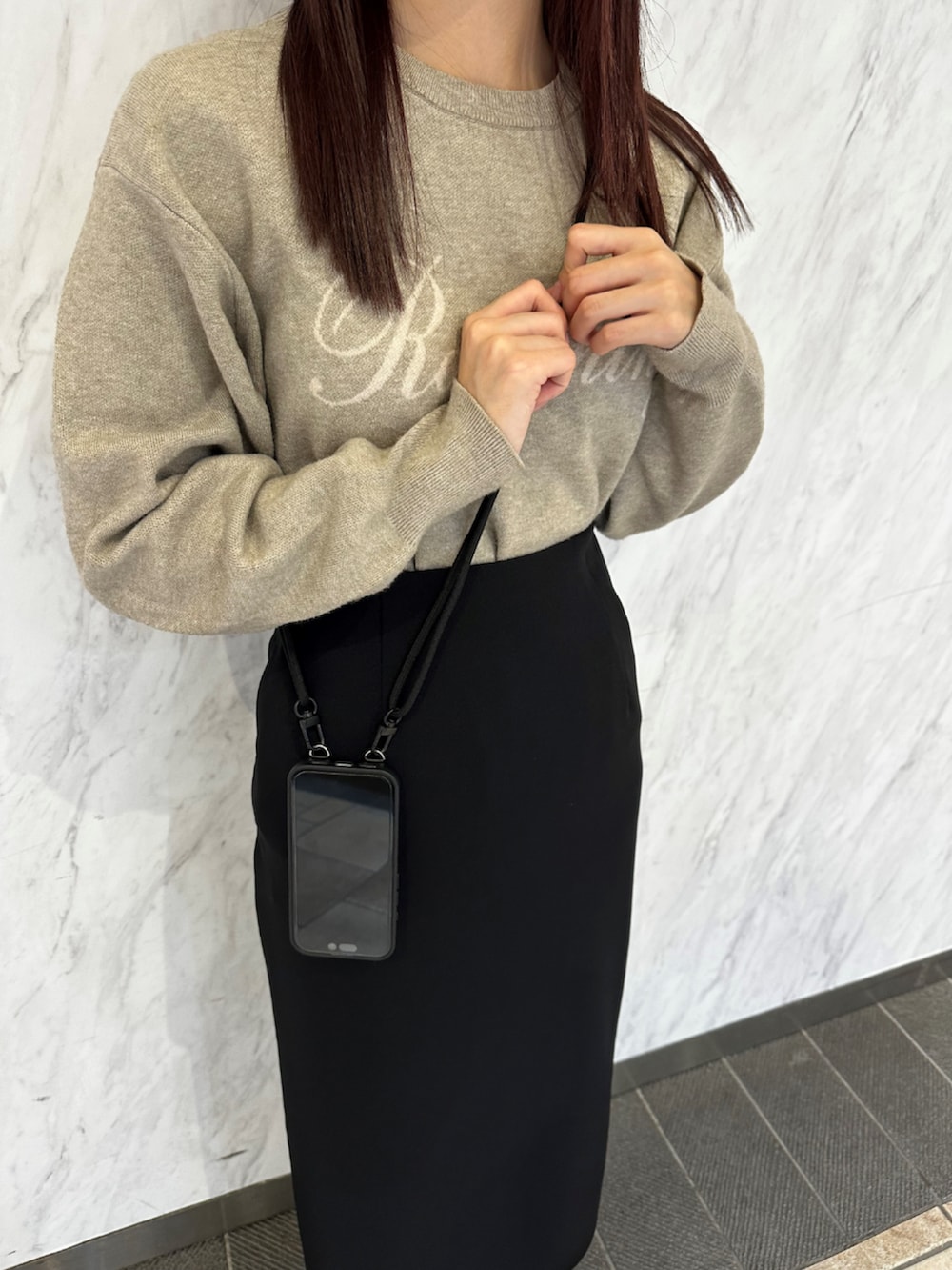 ブラック系のスマホケース/カバーを着用したレディースの春コーディネートの2枚目の写真
