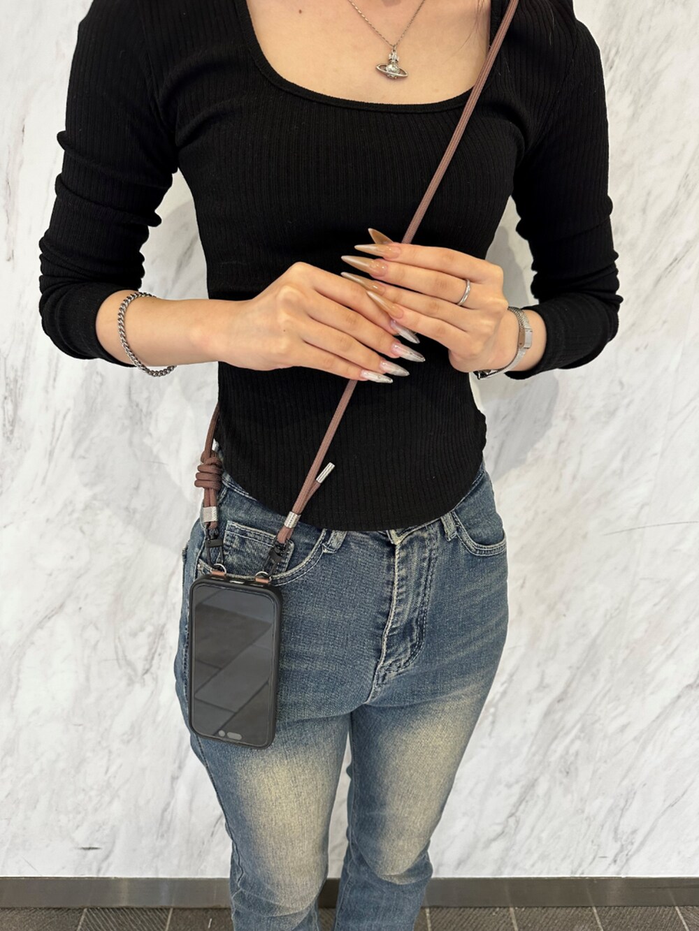 ブラウン系のスマホケース/カバーを着用したレディースの春コーディネートの2枚目の写真