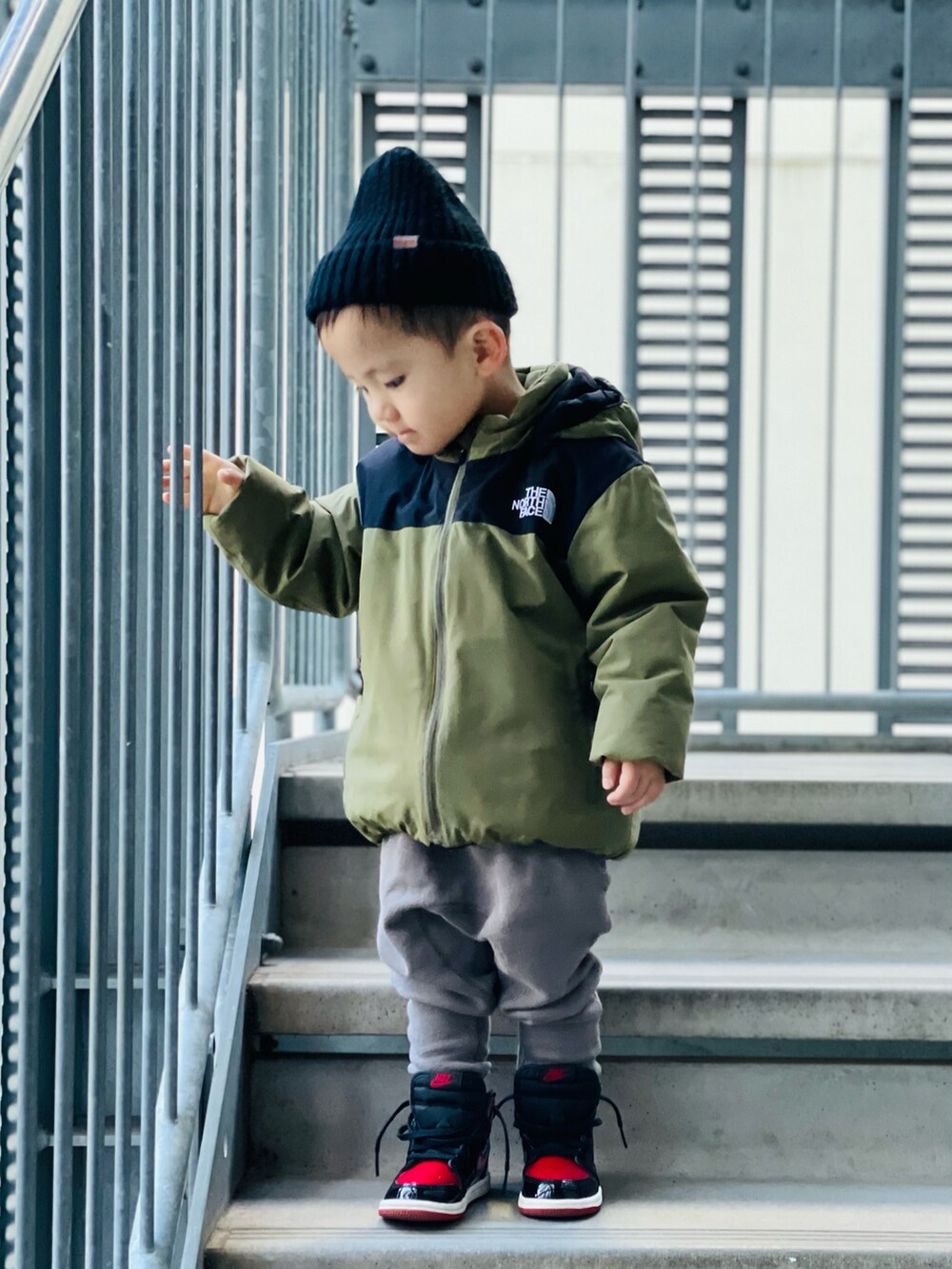 グリーン系のブルゾン、グレー系のその他パンツ、レッド系のスニーカーを着用したキッズの冬コーディネートの2枚目の写真