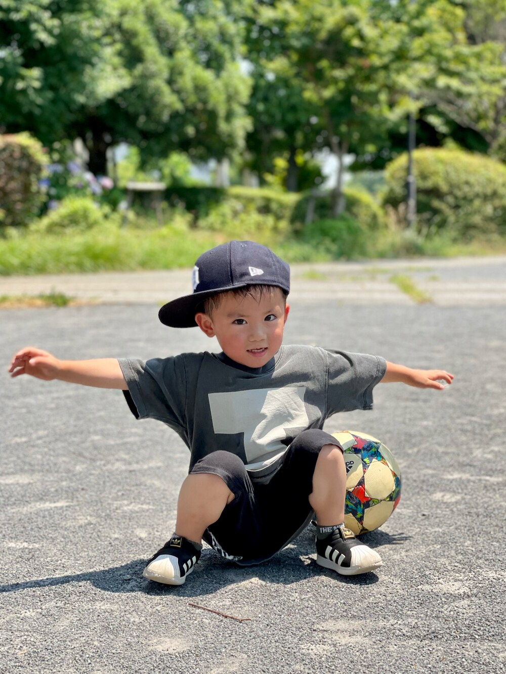 ブラック系のTシャツ/カットソー、ブラック系のスニーカー、ブルー系のキャップを着用したキッズの夏コーディネートの2枚目の写真