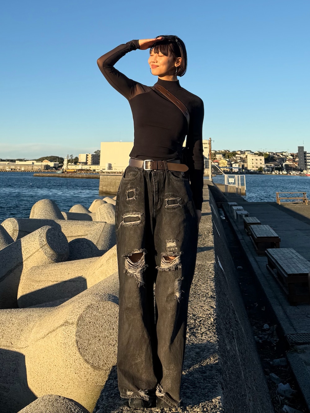 シルバー系のスニーカー、ブラック系のデニムパンツ、ブラウン系のショルダーバッグを着用したレディースの秋コーディネートの2枚目の写真