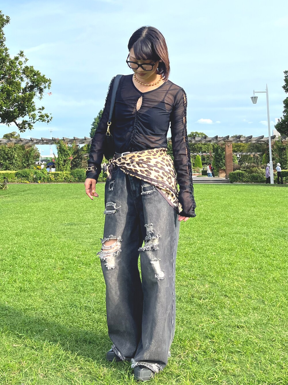 ブラック系のデニムパンツ、ブラック系のスニーカー、ブラック系のTシャツ/カットソーを着用したレディースの秋コーディネートの2枚目の写真