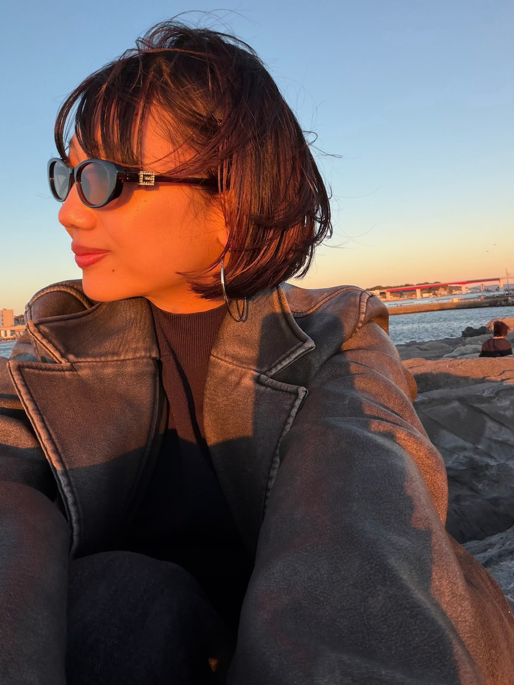 シルバー系のスニーカー、ブラック系のデニムパンツ、ブラウン系のショルダーバッグを着用したレディースの秋コーディネートの3枚目の写真