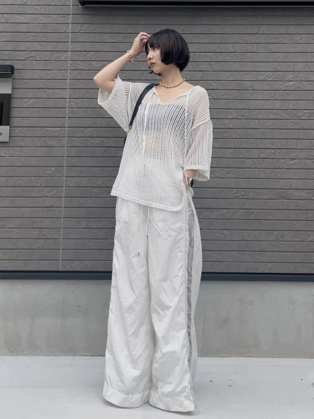 ホワイト系のニット/セーター、ホワイト系のその他パンツ、ブラック系のショルダーバッグを着用したレディースの夏コーディネートの2枚目の写真