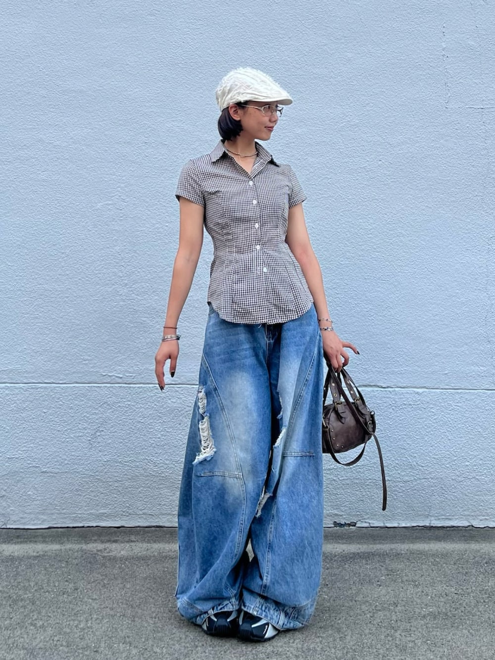 ブルー系のデニムパンツ、ブラウン系のショルダーバッグ、シルバー系のスニーカーを着用したレディースの秋コーディネートの2枚目の写真