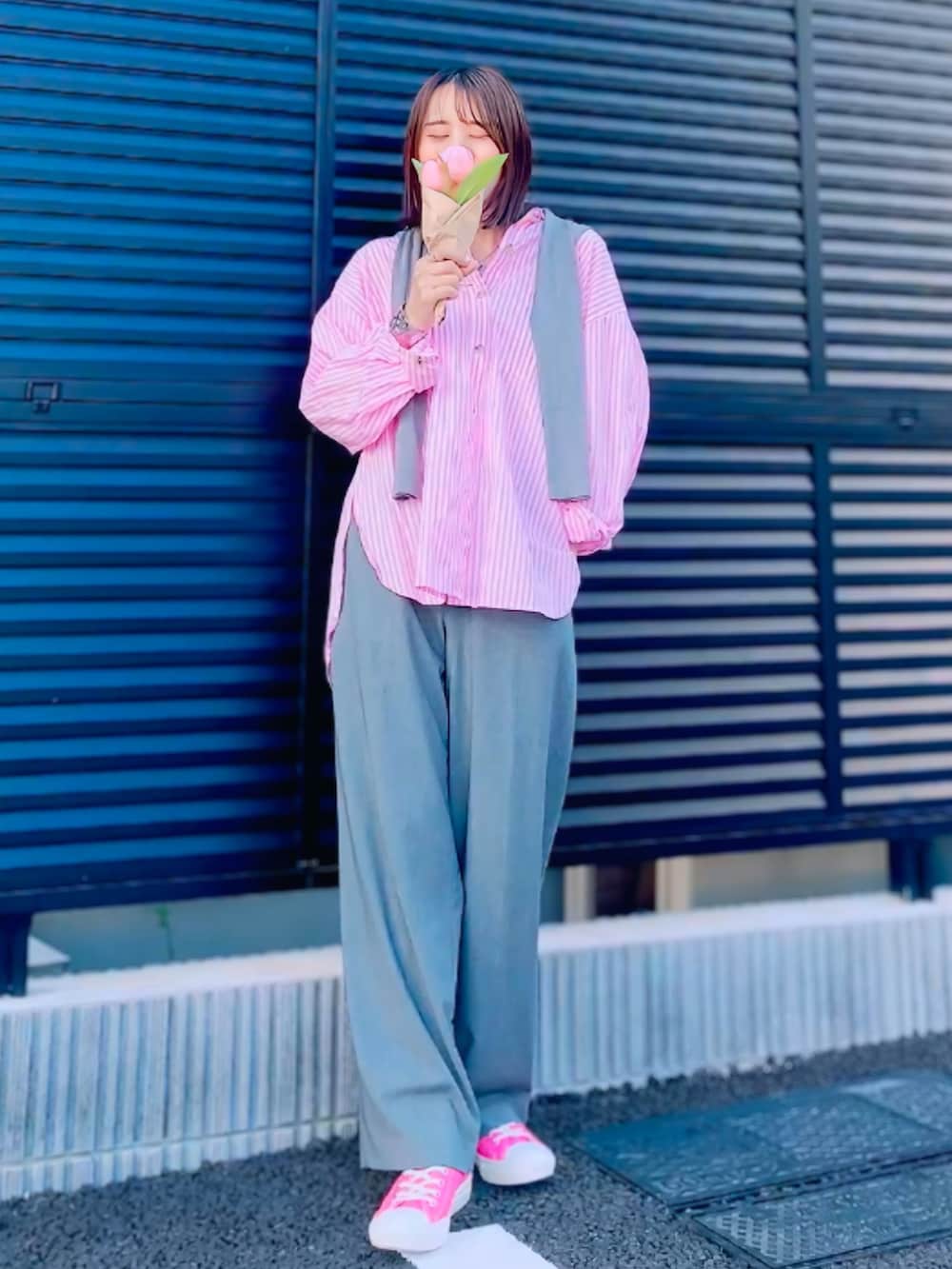 ピンク系のシャツ/ブラウス、グレー系のトップス、グレー系のスラックスを着用したレディースの春コーディネートの2枚目の写真