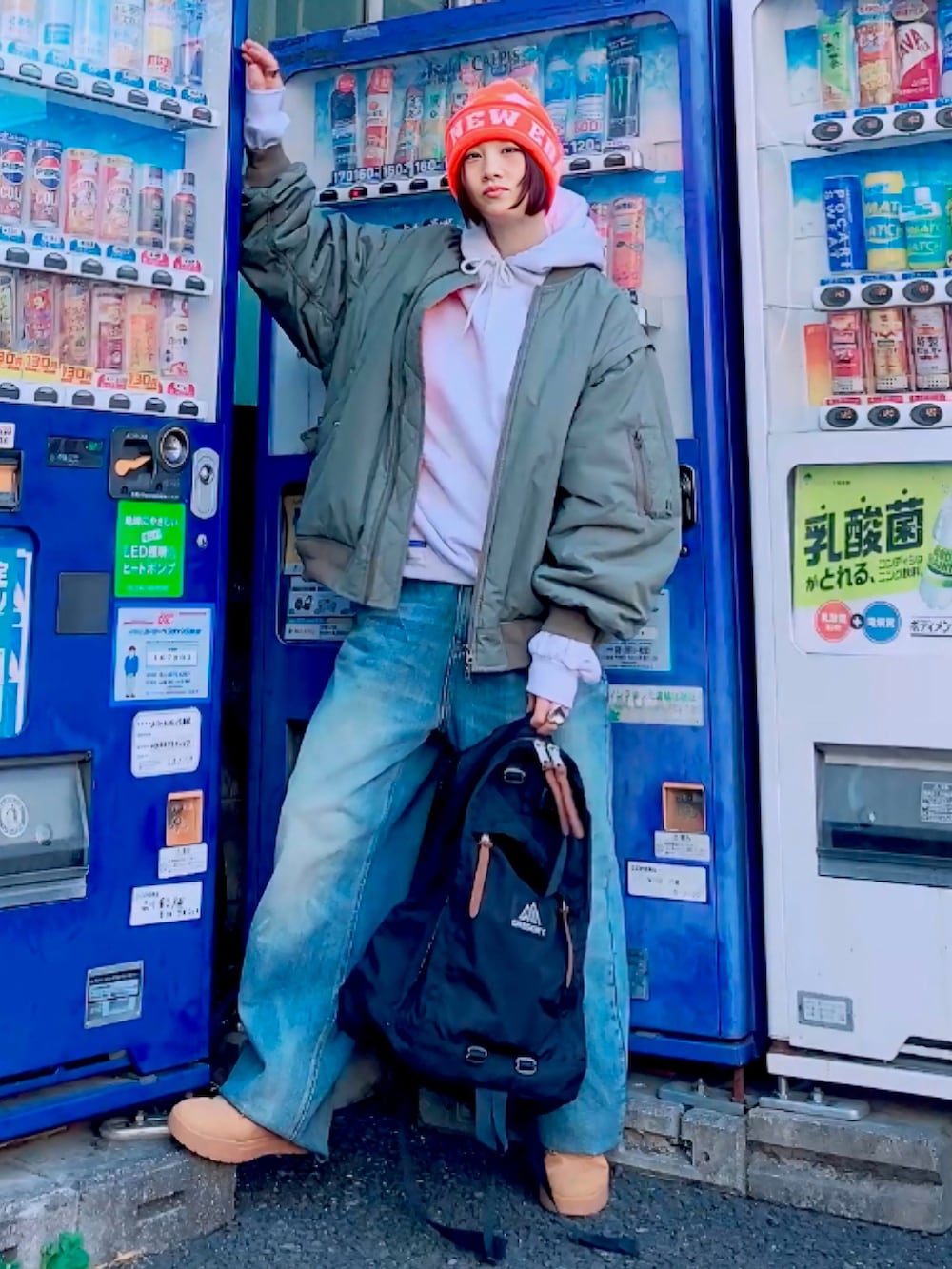 グレー系のパーカー、ブラック系のバックパック/リュック、グリーン系のMA-1を着用したレディースの冬コーディネートの3枚目の写真