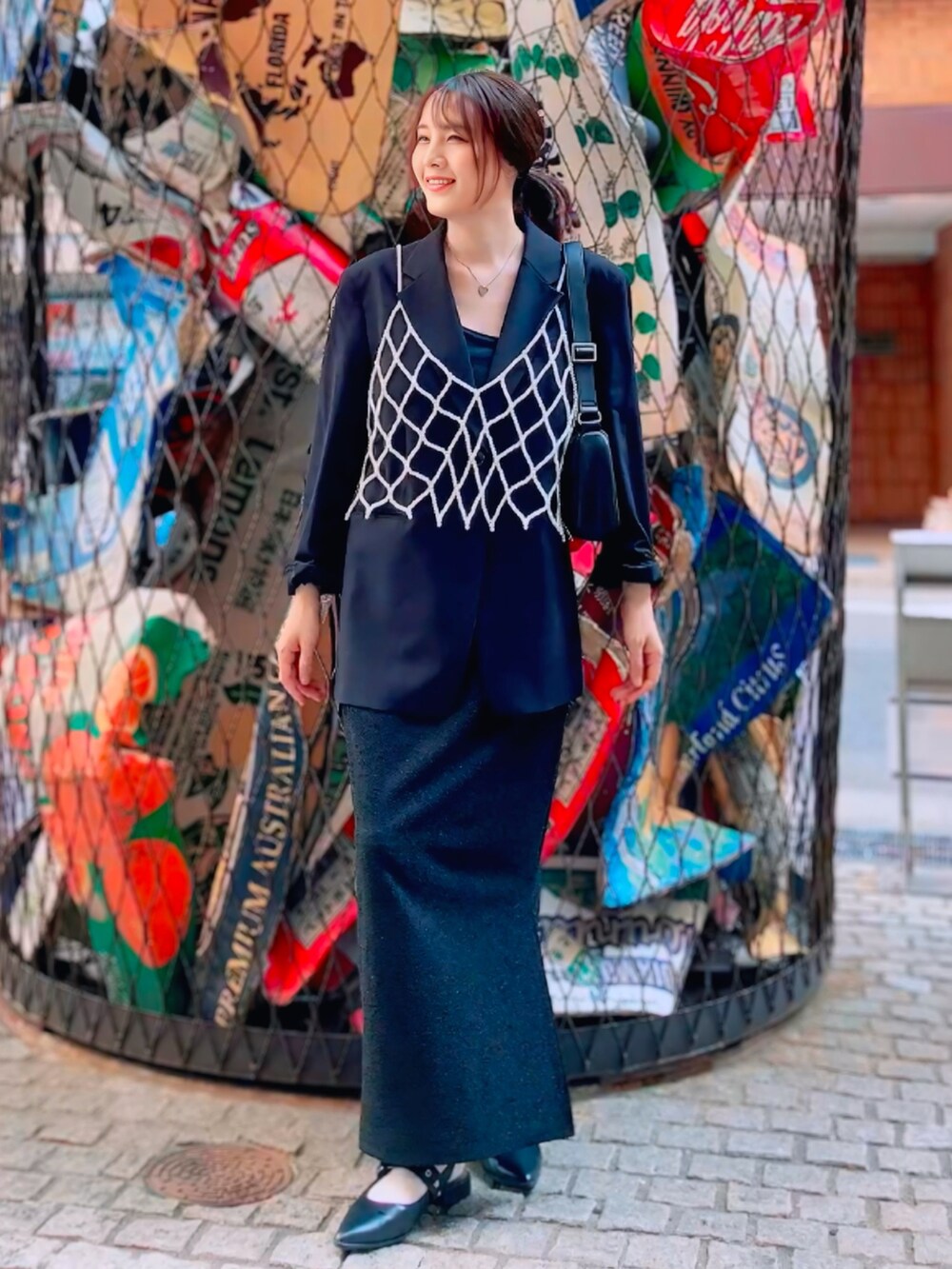 ブラック系のノーカラージャケット、ブラック系のスカート、ホワイト系のベストを着用したレディースの秋コーディネートの3枚目の写真