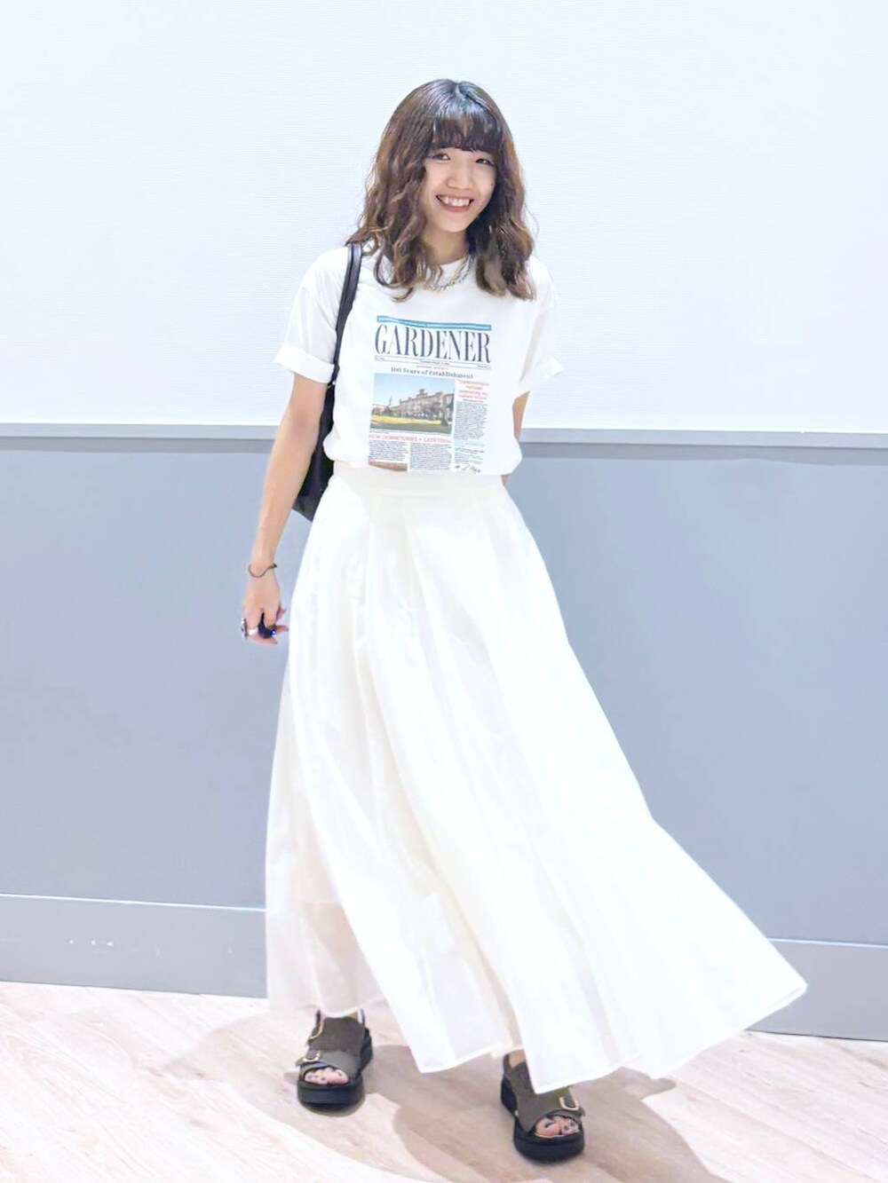 ホワイト系のスカート、ブラウン系のサンダル、ブラウン系のボストンバッグを着用したレディースの秋コーディネートの2枚目の写真