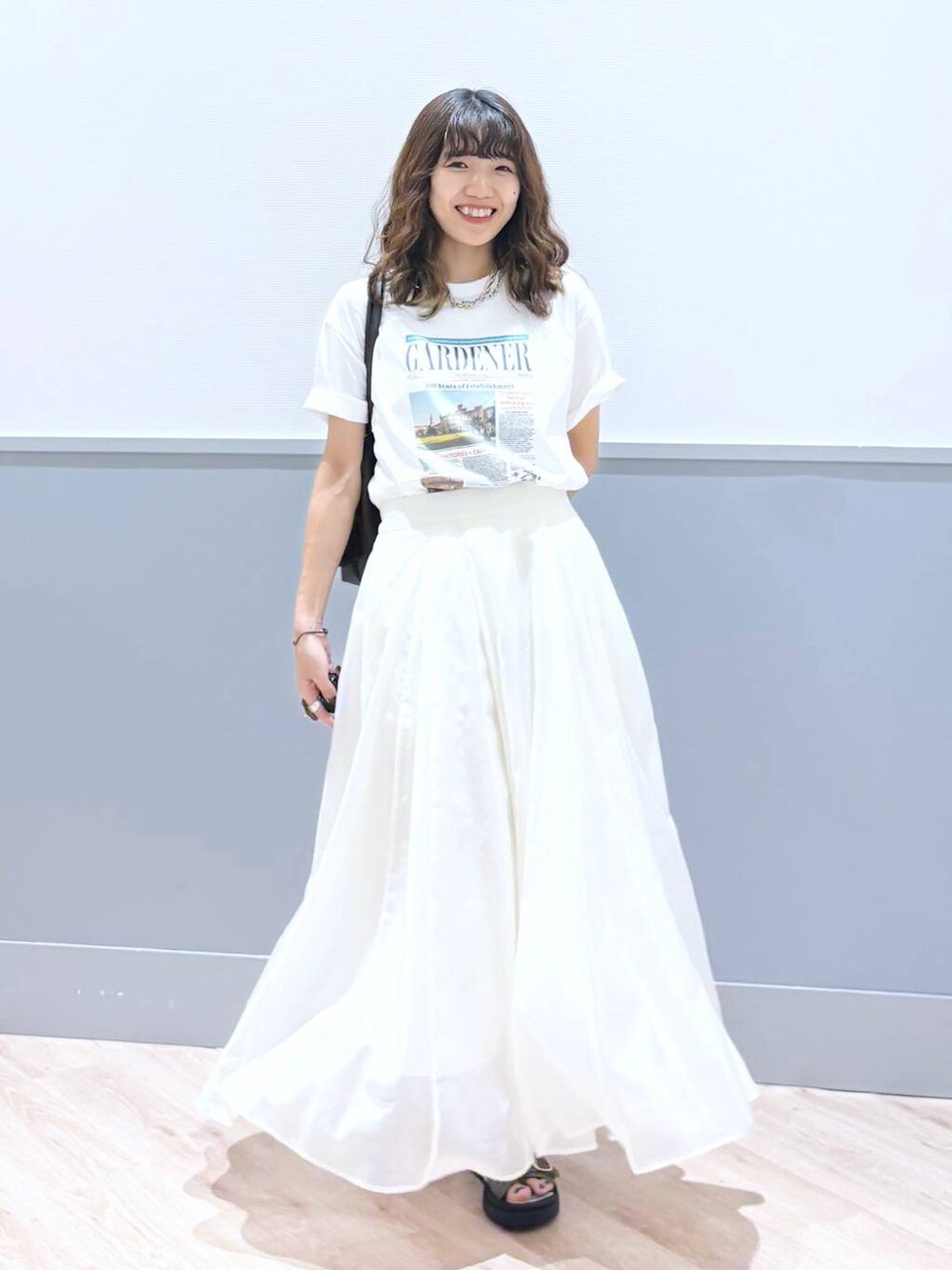 ホワイト系のスカート、ブラウン系のサンダル、ブラウン系のボストンバッグを着用したレディースの秋コーディネートの6枚目の写真