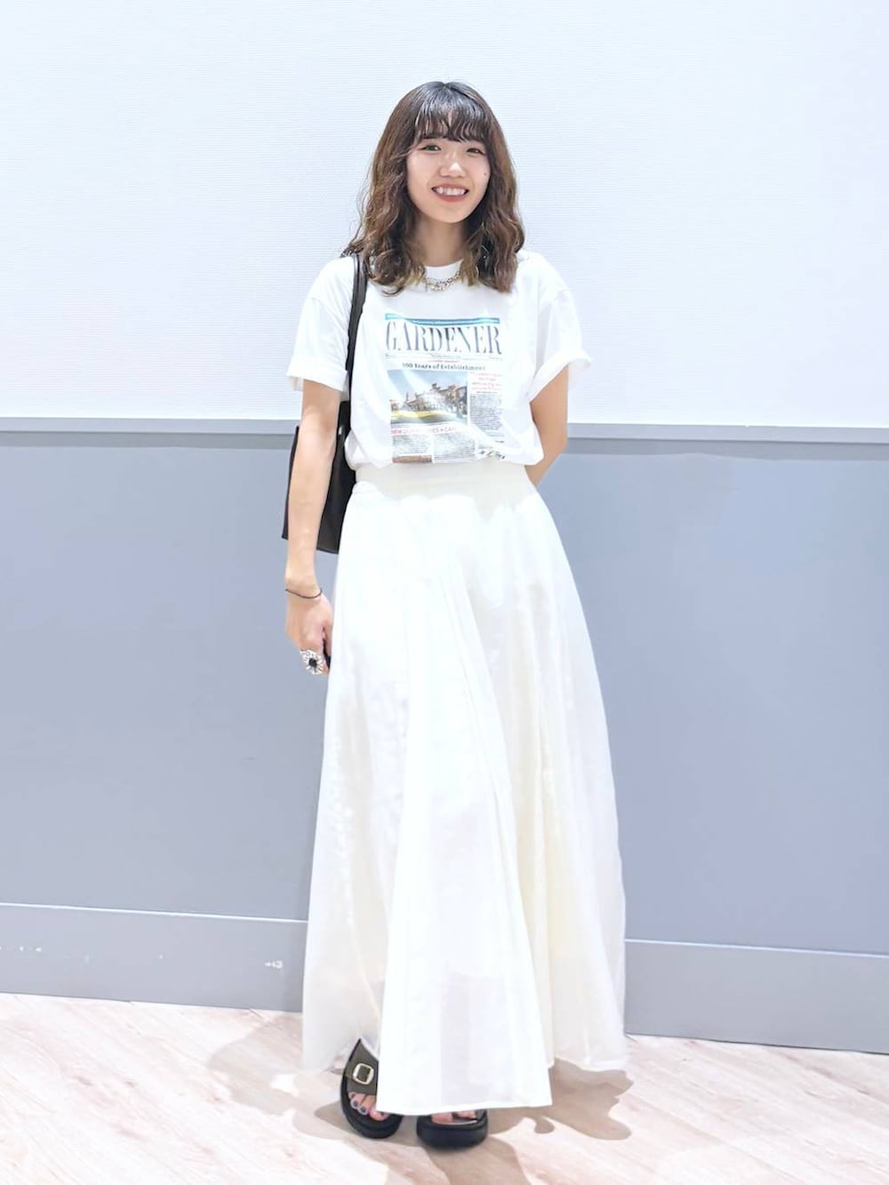 ホワイト系のスカート、ブラウン系のサンダル、ブラウン系のボストンバッグを着用したレディースの秋コーディネートの7枚目の写真