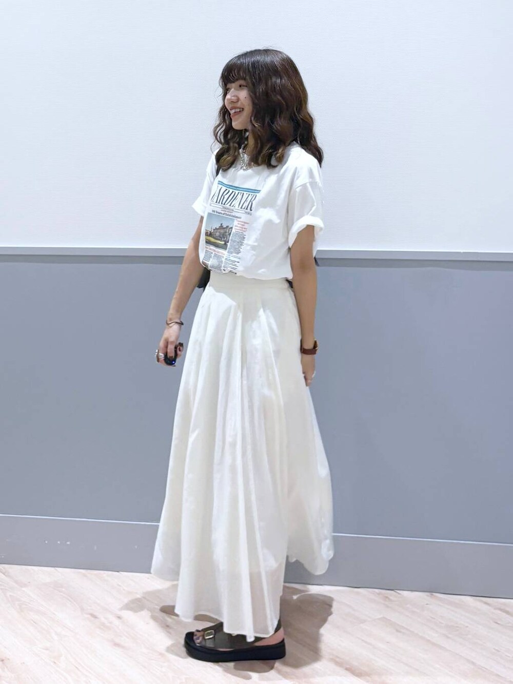 ホワイト系のスカート、ブラウン系のサンダル、ブラウン系のボストンバッグを着用したレディースの秋コーディネートの3枚目の写真