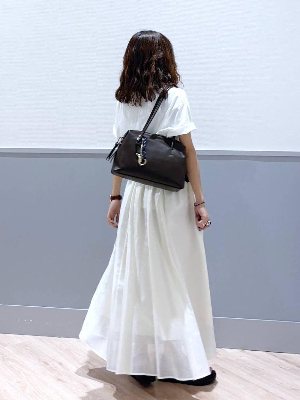 ホワイト系のスカート、ブラウン系のサンダル、ブラウン系のボストンバッグを着用したレディースの秋コーディネートの5枚目の写真