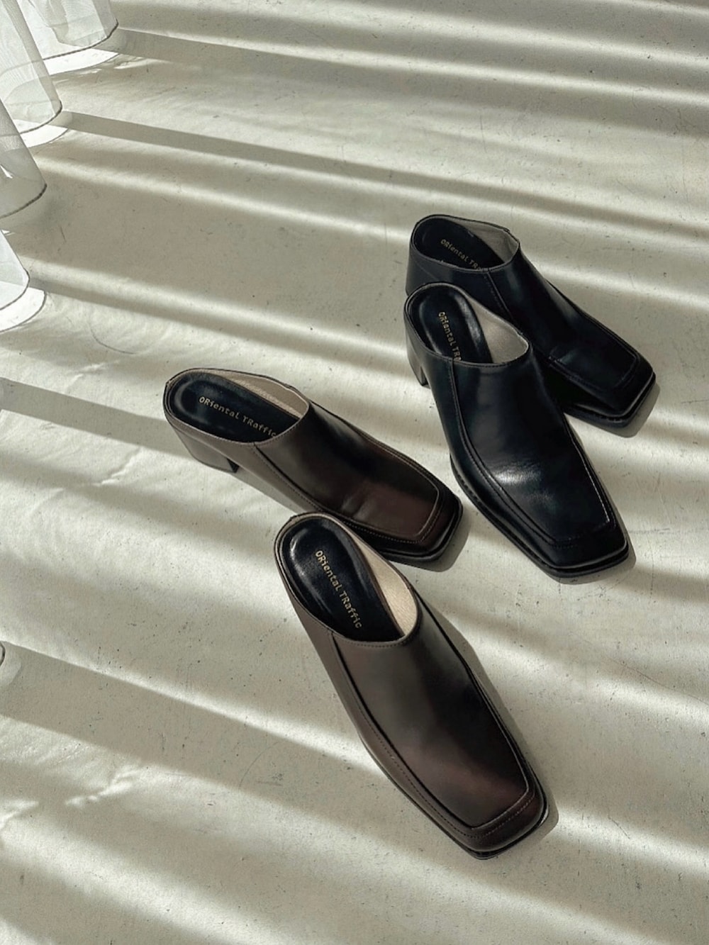 ブラウン系のパンプス、ホワイト系のハンドバッグ、ブルー系のトレンチコートを着用したレディースの春コーディネートの2枚目の写真