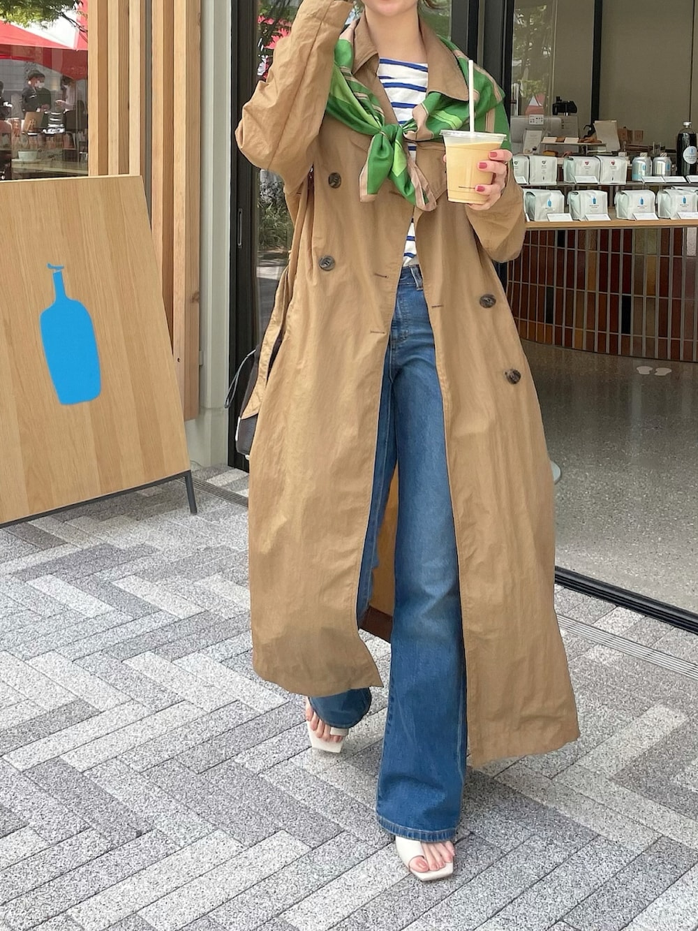 ホワイト系のサンダル、ホワイト系のTシャツ/カットソー、ベージュ系のトレンチコートを着用したレディースの春コーディネートの3枚目の写真