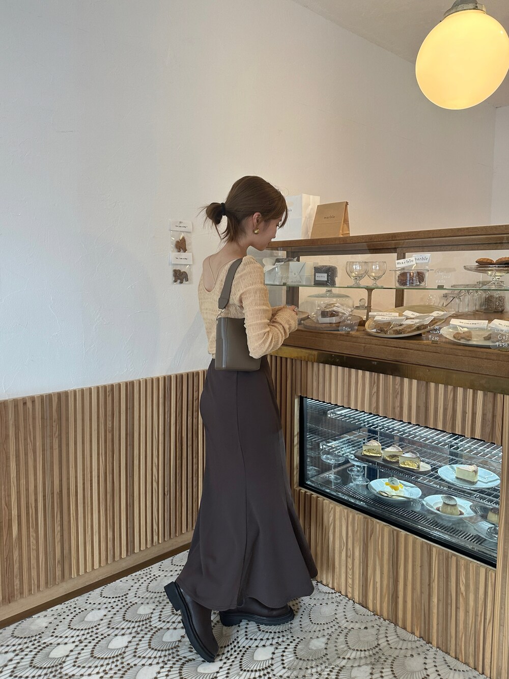 レッド系のブーツ、オレンジ系のTシャツ/カットソー、ブラウン系のスカートを着用したレディースの秋コーディネートの4枚目の写真