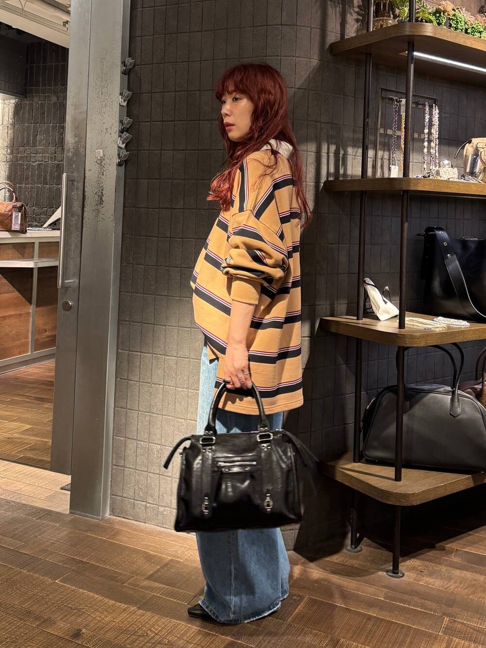 ブルー系のデニムパンツ、ブラック系のローファー、ブラック系のボストンバッグを着用したレディースの秋コーディネートの4枚目の写真