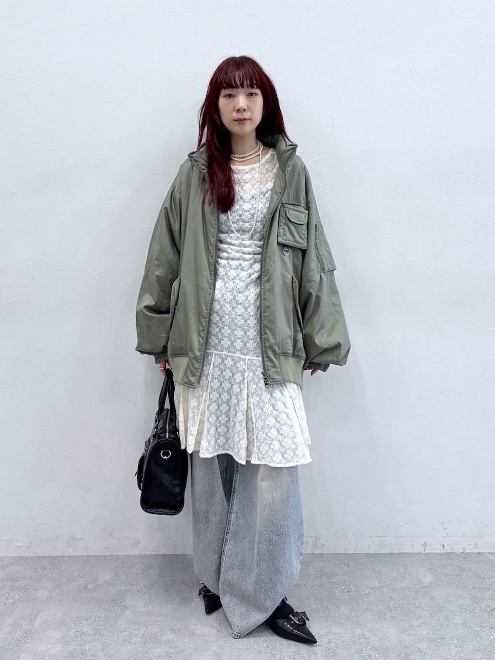 ブルー系のデニムパンツ、ブラック系のパンプス、グリーン系のブルゾンを着用したレディースの秋コーディネートの3枚目の写真