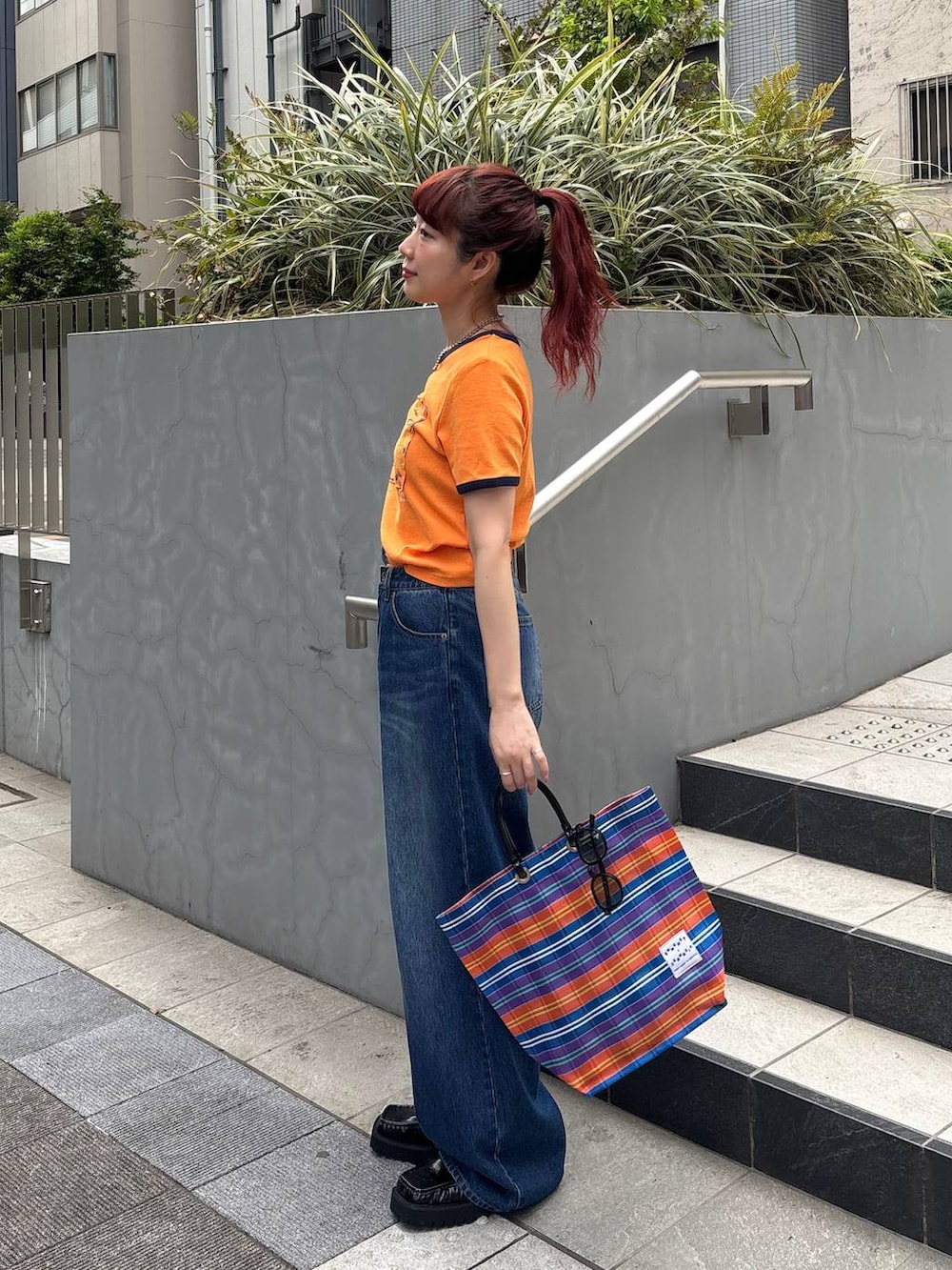 ブラック系のローファー、オレンジ系のTシャツ/カットソー、ブルー系のデニムパンツを着用したレディースの夏コーディネートの3枚目の写真