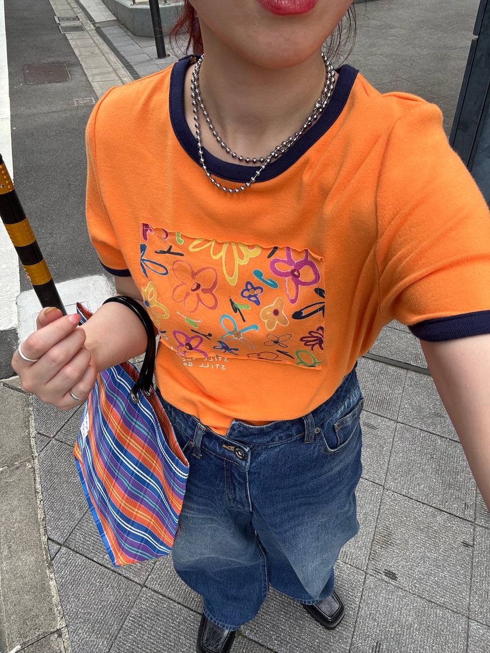 ブラック系のローファー、オレンジ系のTシャツ/カットソー、ブルー系のデニムパンツを着用したレディースの夏コーディネートの8枚目の写真