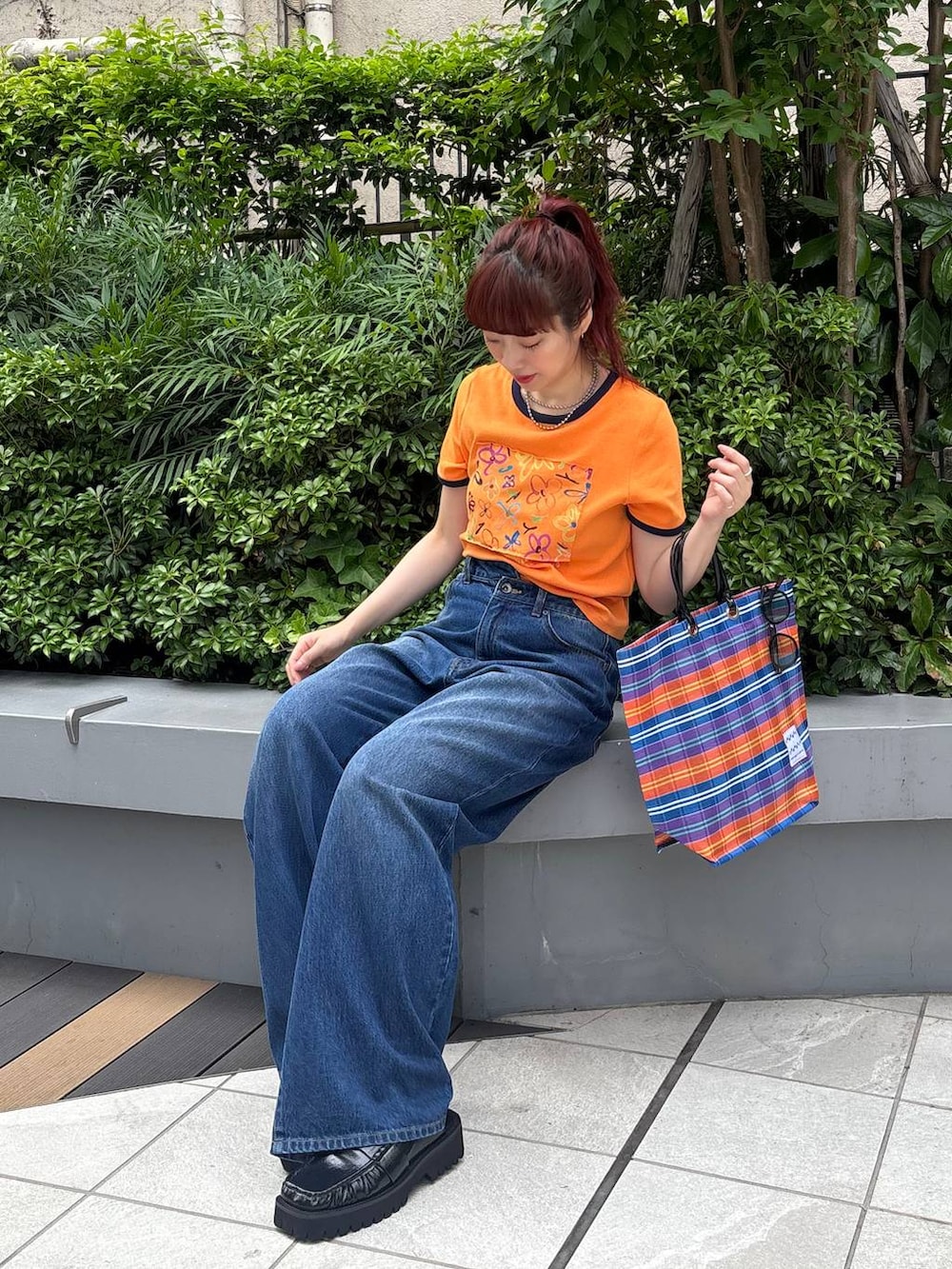 ブラック系のローファー、オレンジ系のTシャツ/カットソー、ブルー系のデニムパンツを着用したレディースの夏コーディネートの5枚目の写真