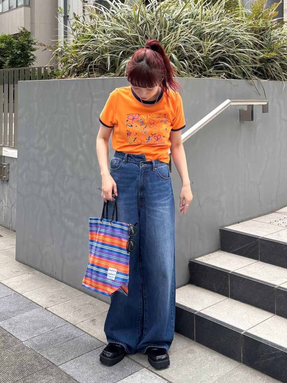 ブラック系のローファー、オレンジ系のTシャツ/カットソー、ブルー系のデニムパンツを着用したレディースの夏コーディネートの7枚目の写真