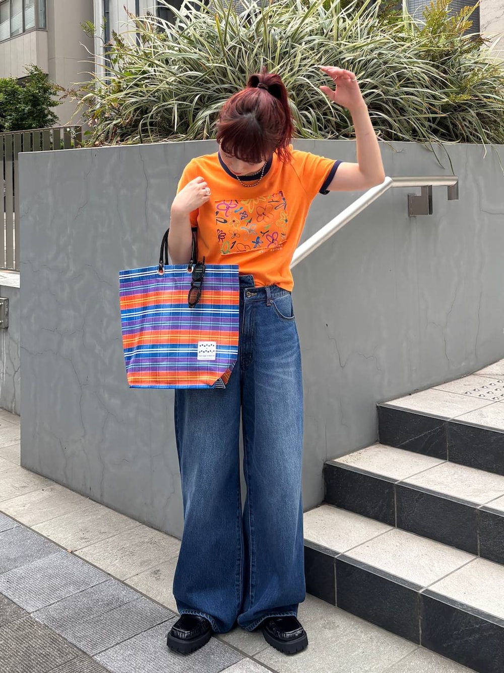 ブラック系のローファー、オレンジ系のTシャツ/カットソー、ブルー系のデニムパンツを着用したレディースの夏コーディネートの2枚目の写真