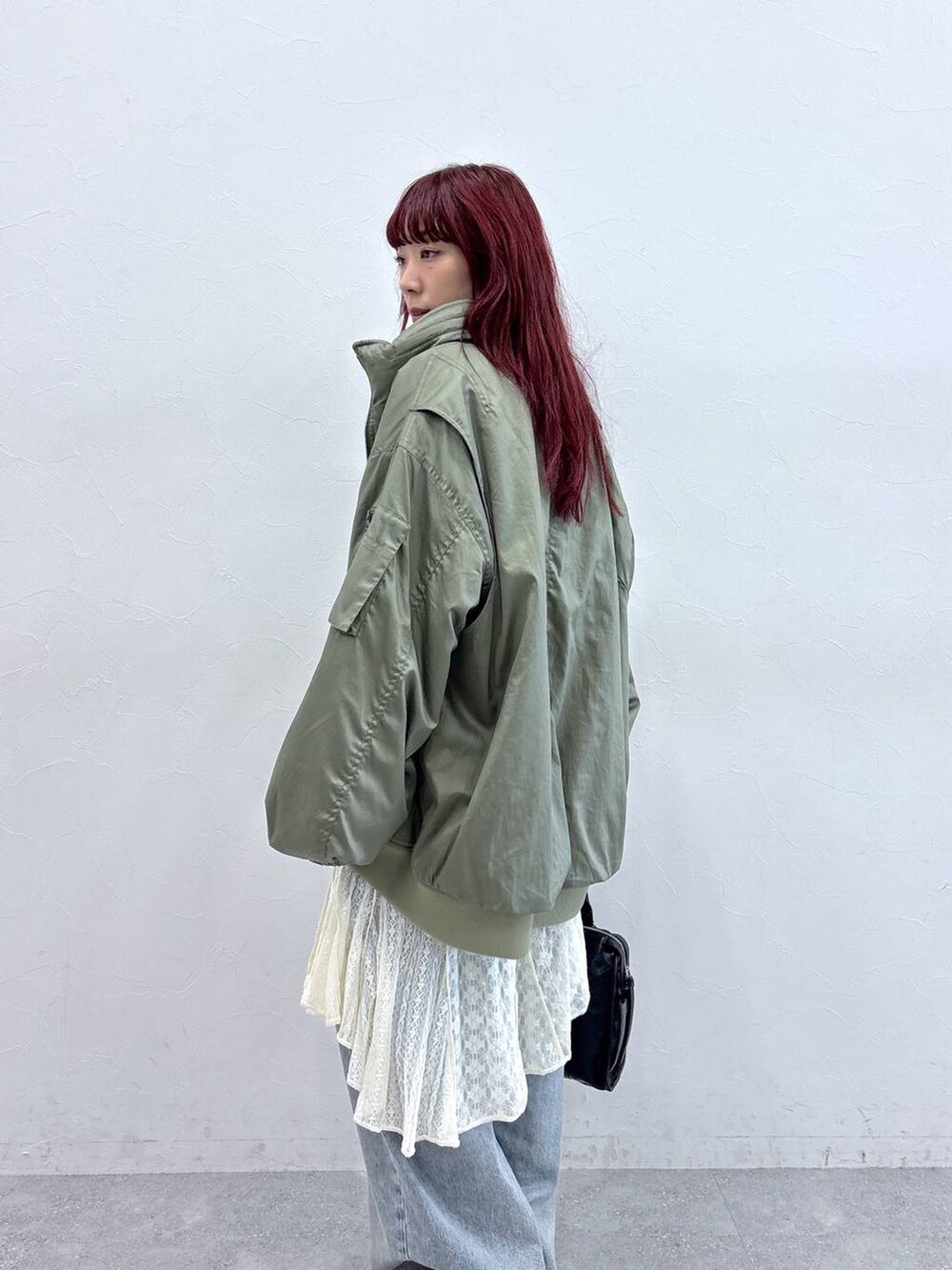 ブルー系のデニムパンツ、ブラック系のパンプス、グリーン系のブルゾンを着用したレディースの秋コーディネートの2枚目の写真