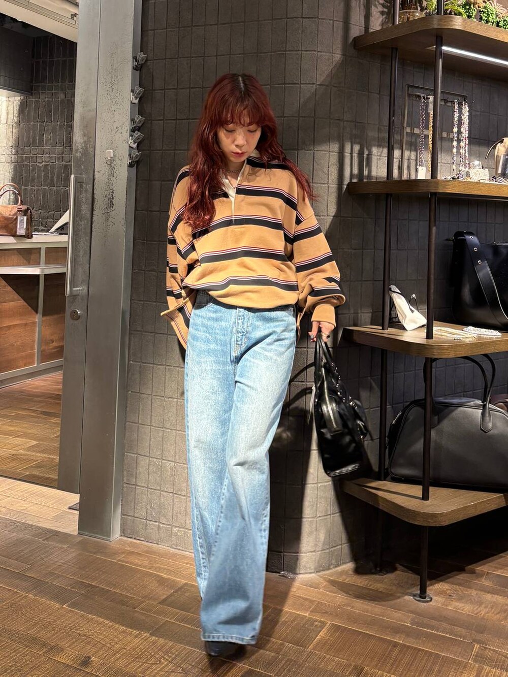 ブルー系のデニムパンツ、ブラック系のローファー、ブラック系のボストンバッグを着用したレディースの秋コーディネートの2枚目の写真