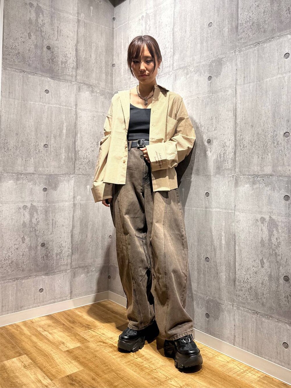 ブラウン系のデニムパンツ、ブラック系のスニーカー、ベージュ系のシャツ/ブラウスを着用したレディースの秋コーディネートの5枚目の写真