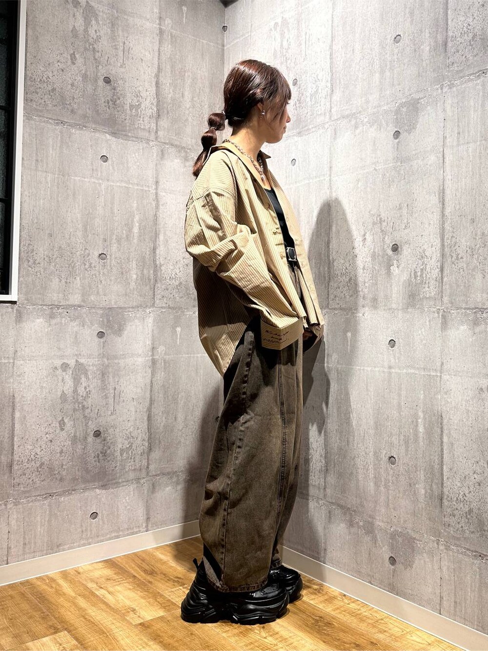 ブラウン系のデニムパンツ、ブラック系のスニーカー、ベージュ系のシャツ/ブラウスを着用したレディースの秋コーディネートの4枚目の写真