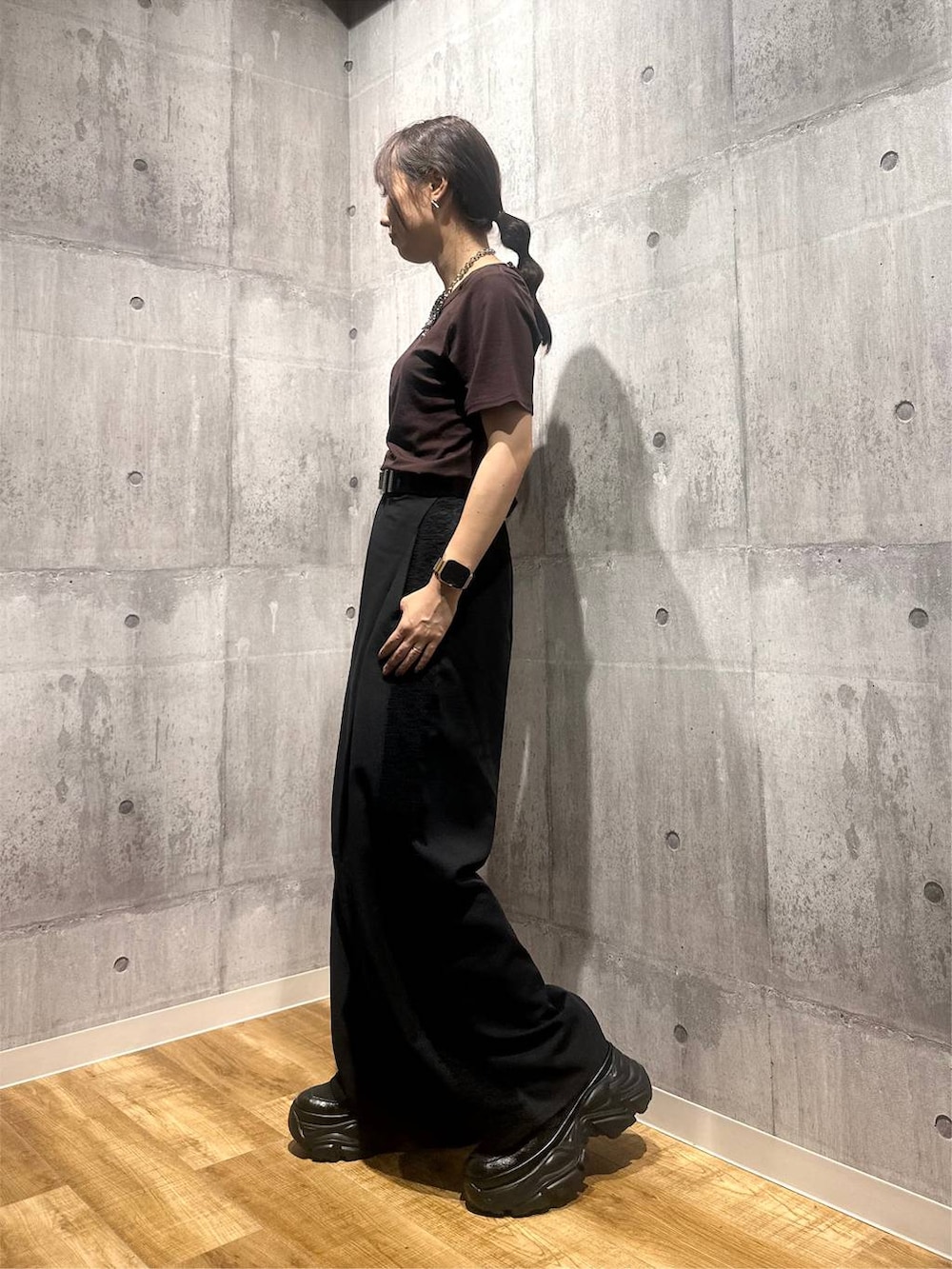 ブラウン系のTシャツ/カットソー、ブラック系のスラックス、ブラック系のスニーカーを着用したレディースの秋コーディネートの4枚目の写真