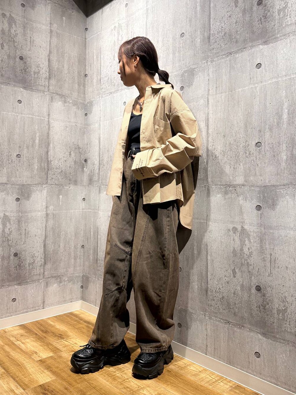 ブラウン系のデニムパンツ、ブラック系のスニーカー、ベージュ系のシャツ/ブラウスを着用したレディースの秋コーディネートの2枚目の写真