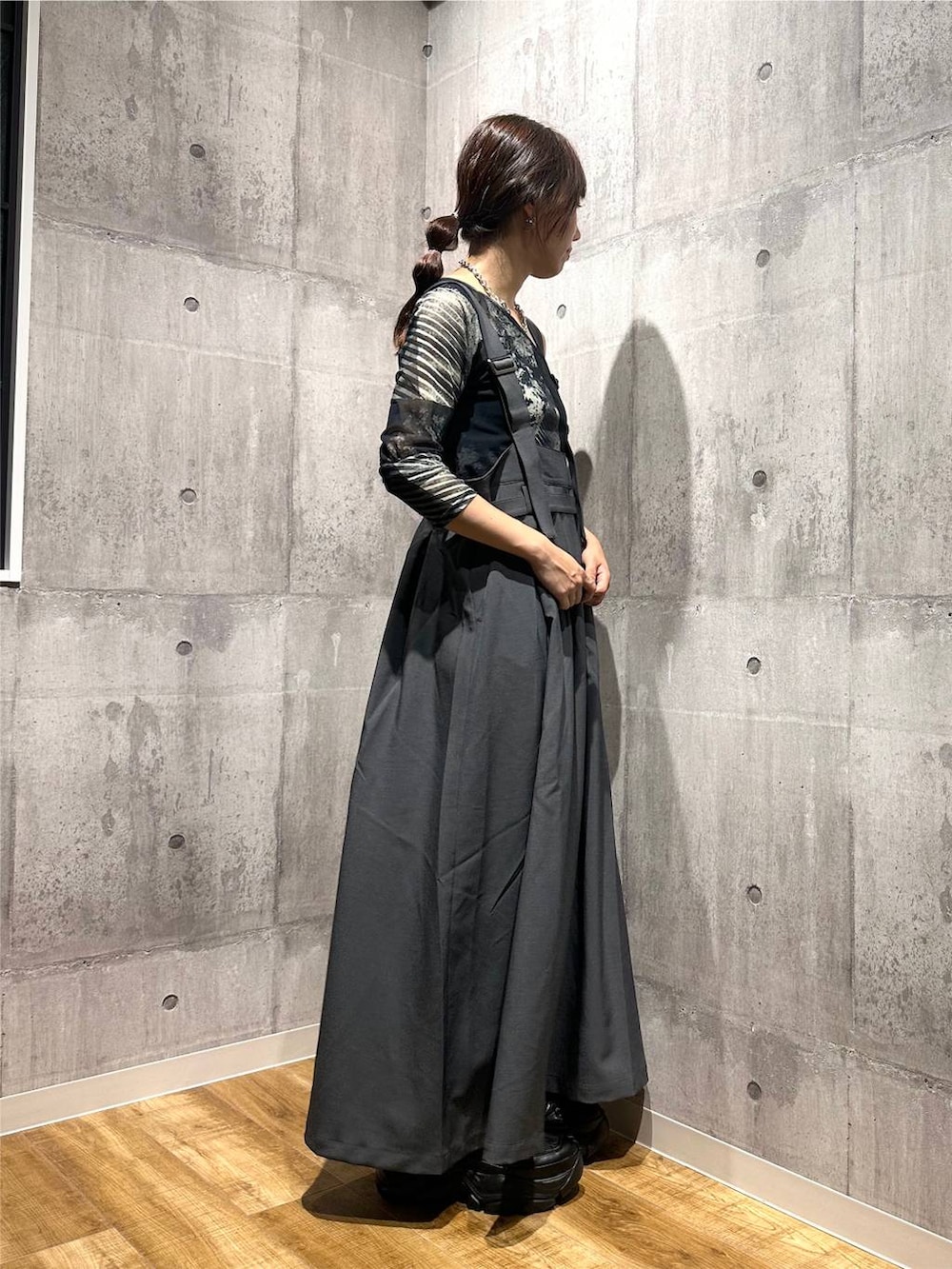 グレー系のジャンパースカート、ブラック系のスニーカー、グレー系のTシャツ/カットソーを着用したレディースの秋コーディネートの4枚目の写真