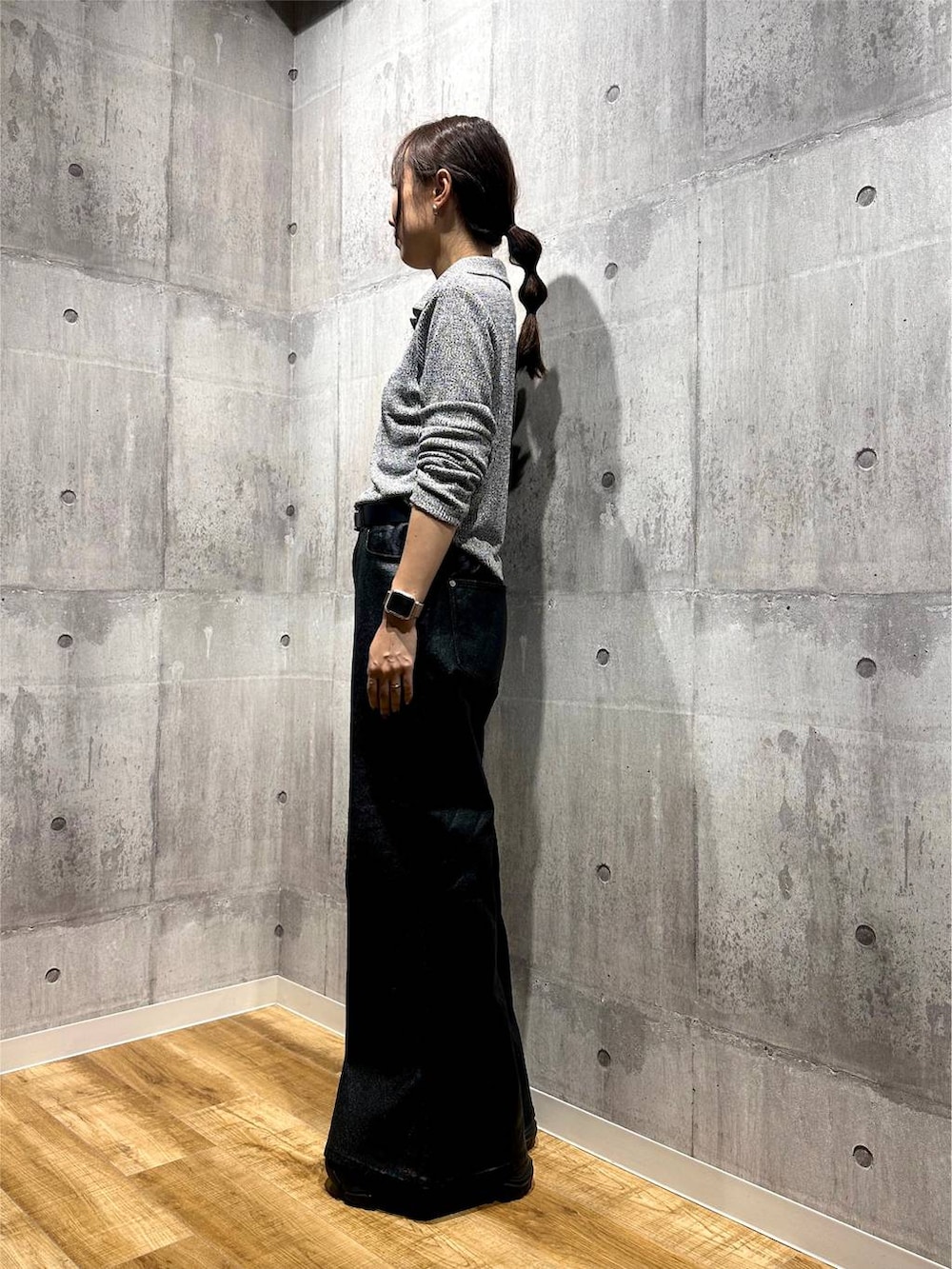 ブラック系のデニムパンツ、ブラック系のスニーカー、グレー系のニット/セーターを着用したレディースの秋コーディネートの4枚目の写真