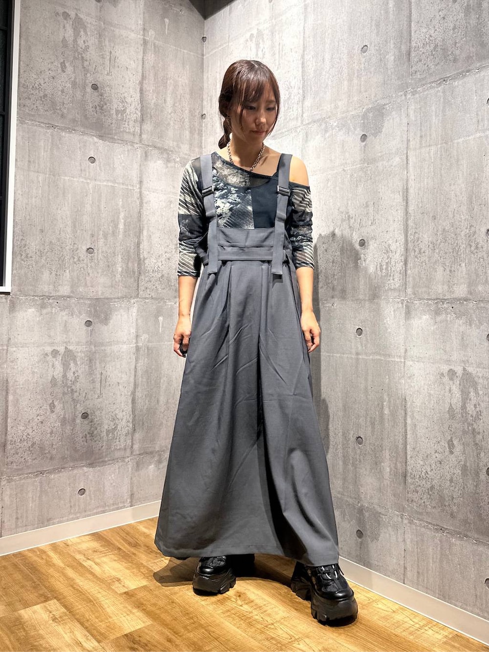 グレー系のジャンパースカート、ブラック系のスニーカー、グレー系のTシャツ/カットソーを着用したレディースの秋コーディネートの5枚目の写真