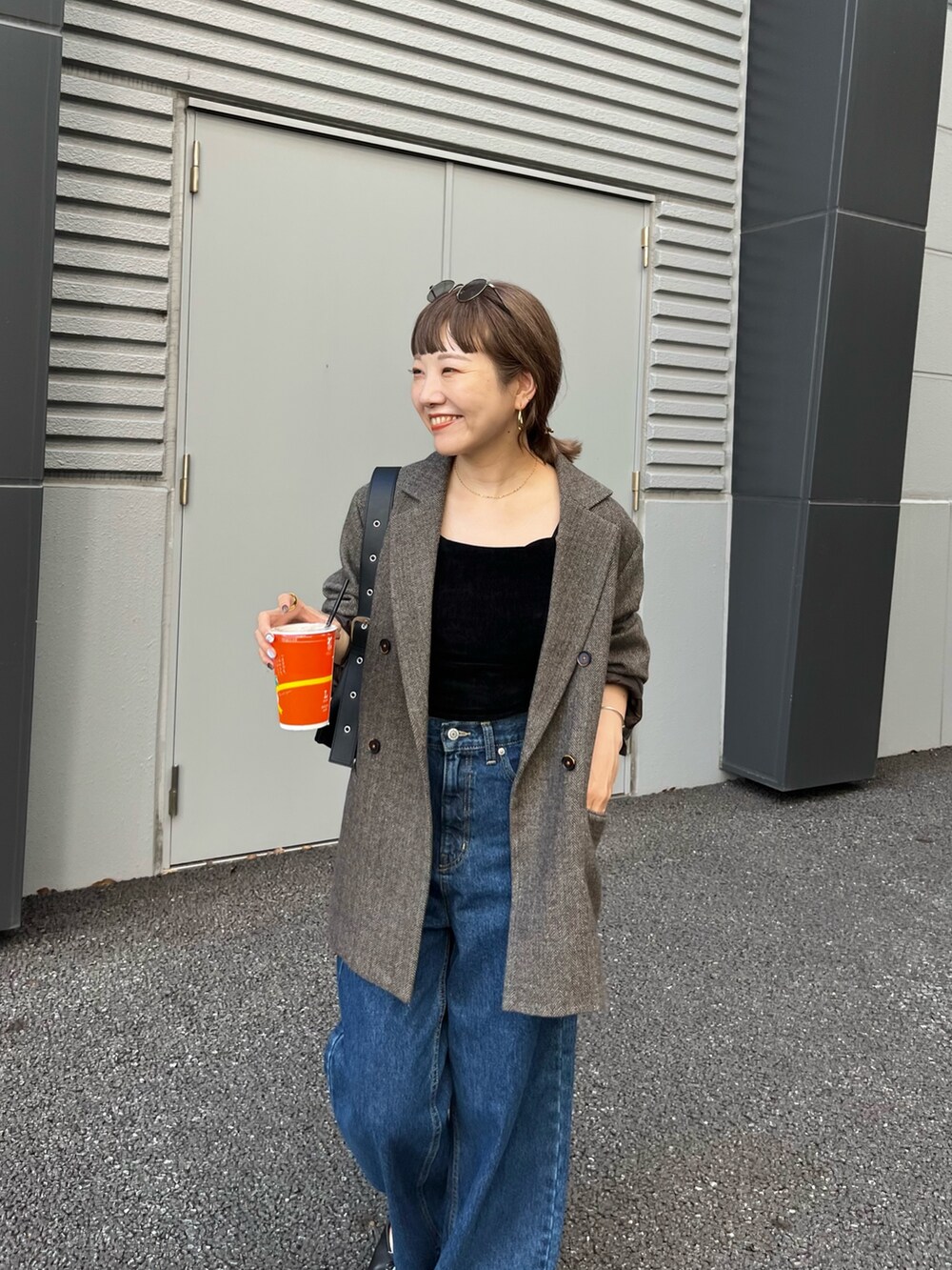 ブラウン系のテーラードジャケット、ブルー系のデニムパンツ、ブラック系のトートバッグを着用したレディースの夏コーディネートの3枚目の写真