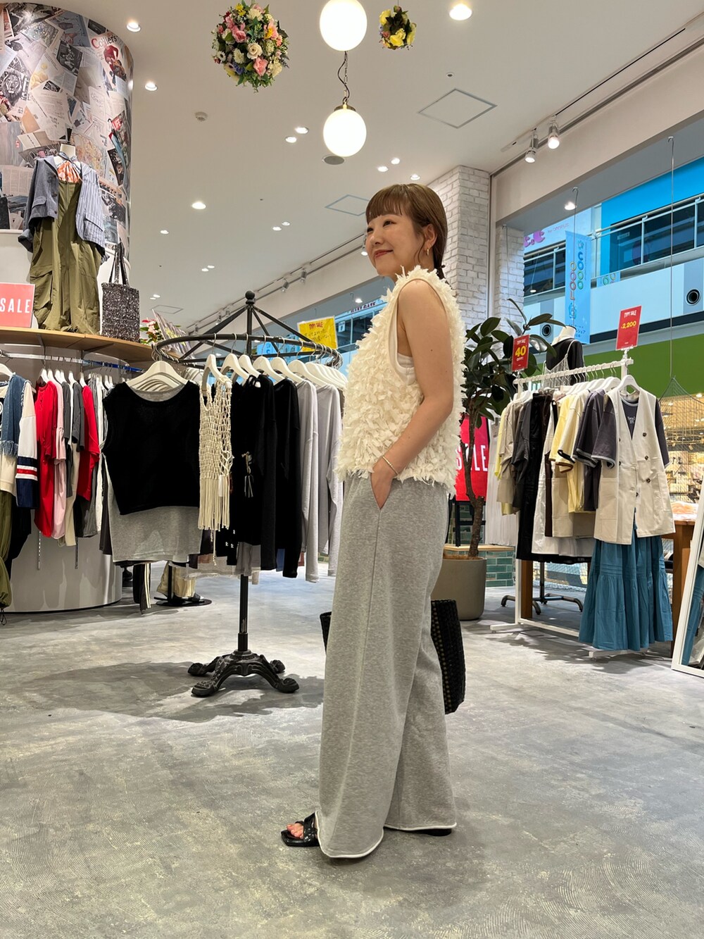 ホワイト系のベスト、ホワイト系のタンクトップ、グレー系のスウェットパンツを着用したレディースの夏コーディネートの2枚目の写真