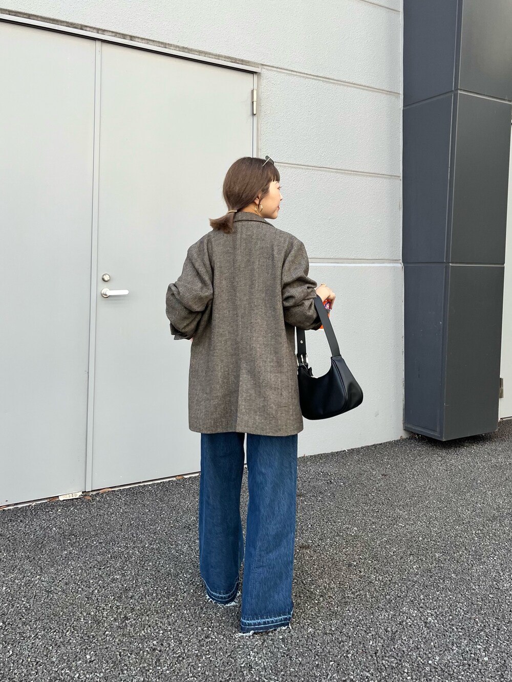 ブラウン系のテーラードジャケット、ブルー系のデニムパンツ、ブラック系のトートバッグを着用したレディースの夏コーディネートの2枚目の写真